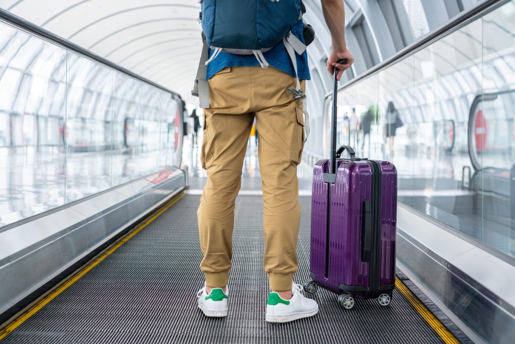 Hombre camina por el aeropuerto con su maleta