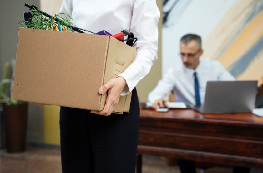 Mujer carga una caja tras ser despedida de su trabajo