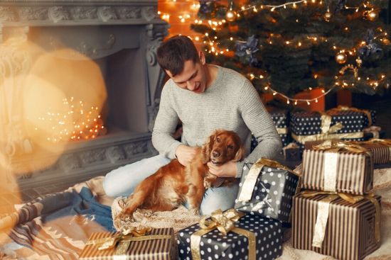 Hombre joven en navidad abraza a su perro