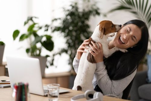 Mujer joven sostiene a su mascota en brazos mientras sonríe