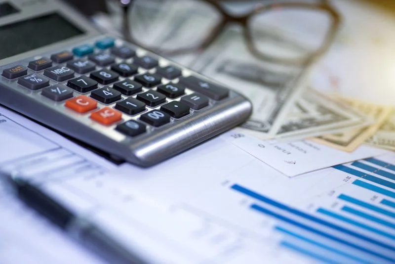 Calculadora sobre la mesa junto con papeles y anteojos